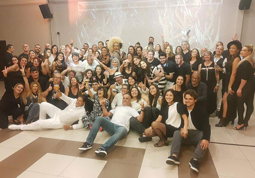 Drag Queen interagindo com participantes em palco iluminado