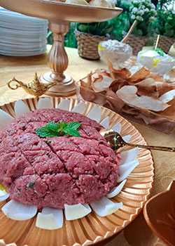Kibe cru decorado com hortelã e cebola em buffet árabe