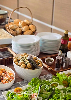 Mesa com saladas, pães e pratos prontos para buffet de churrasco